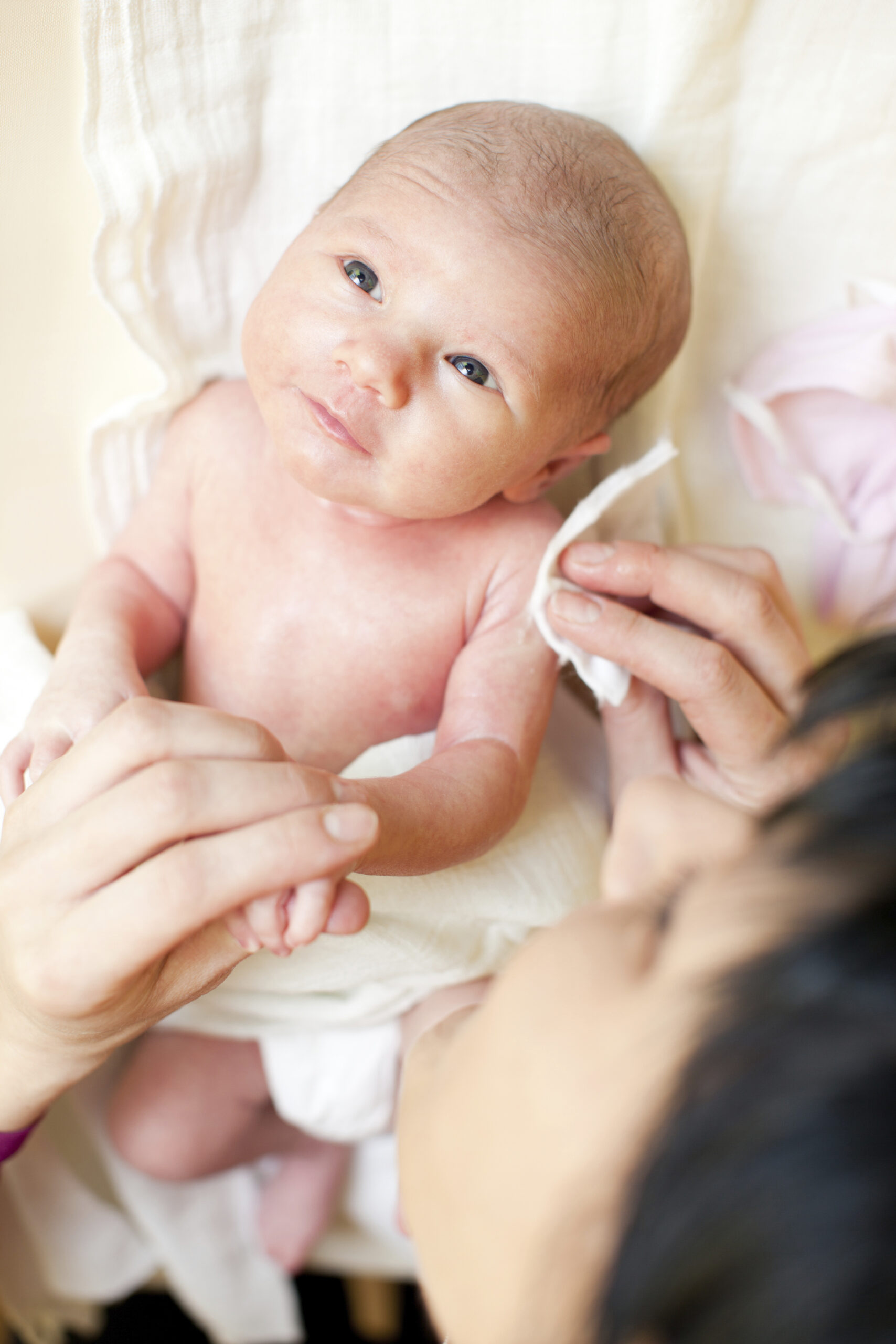 Mom wiping newborn baby. with cotton wipes